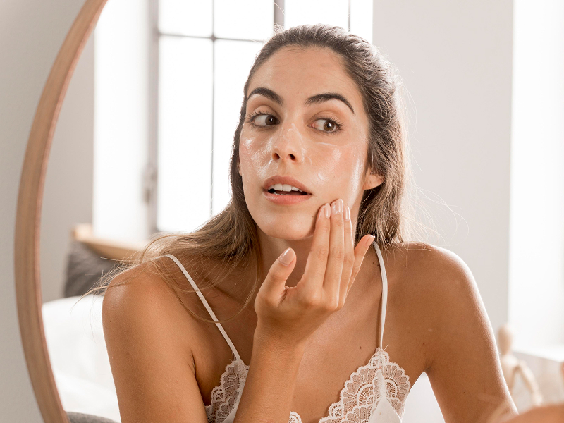Mulher aplicando creme no rosto